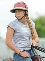 pretty female polo groom wearing pink polo helmeton horseback, waist up
